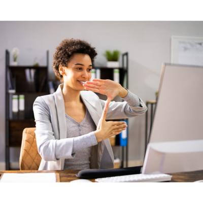 Woman is signing in front of a computer monitor