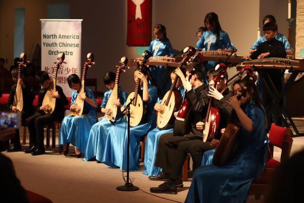 Musicians from the North America Youth Chinese Orchestra perform with stringed instruments.