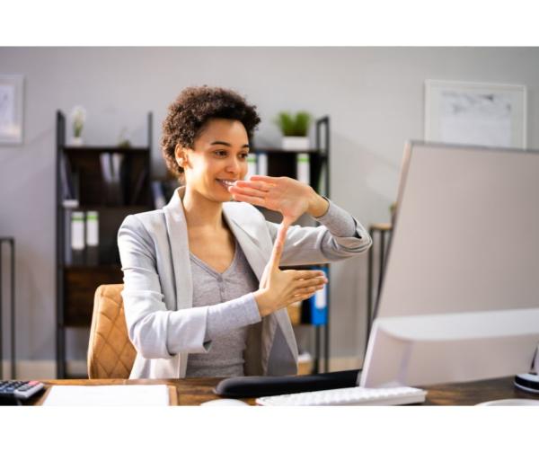 Woman is signing in front of a computer monitor