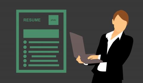 woman holding computer next to resume 
