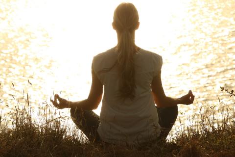 woman meditating by a lake