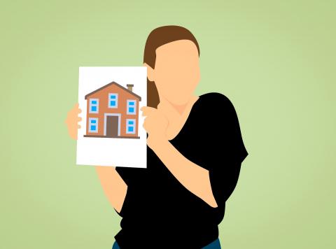 person holding up photo of house
