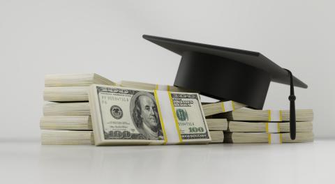 stacks of bills with a graduation cap