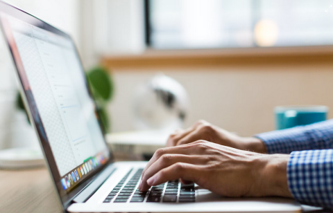 a close up of hands typing on a laptop