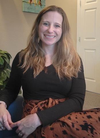 photo of a woman sitting with a broad, happy smile 