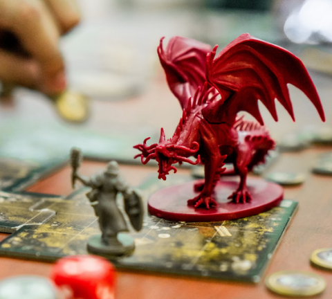 photo of a close up of a red dragon figure fighting a grey warrior figure