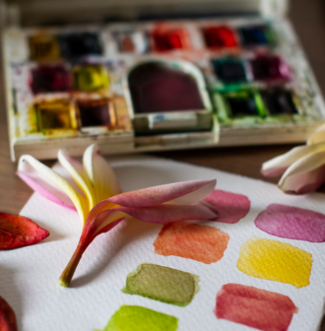 close up of a water color palette, a flower, and swatched colors matching the colors in the flower