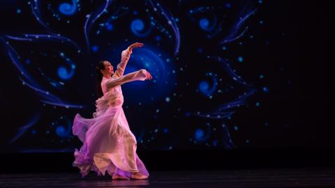 woman dancing with pink dress and blue swirl background