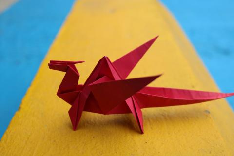 A red origami dragon on a yellow and blue background