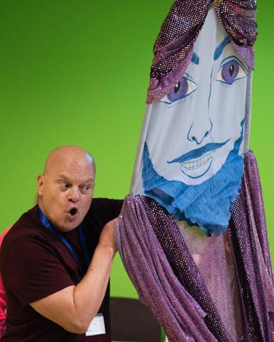 Man holding a large puppet with a face
