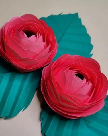 Red paper flowers with green leaves on a neutral background