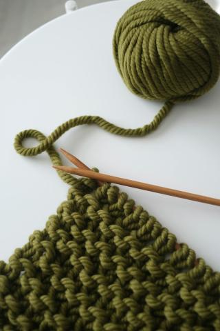 Green knitted piece on a white table