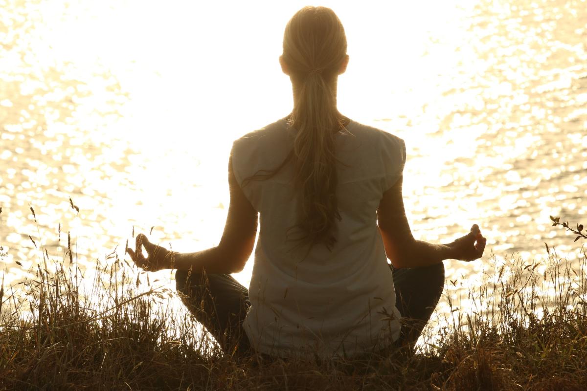 woman meditating by a lake