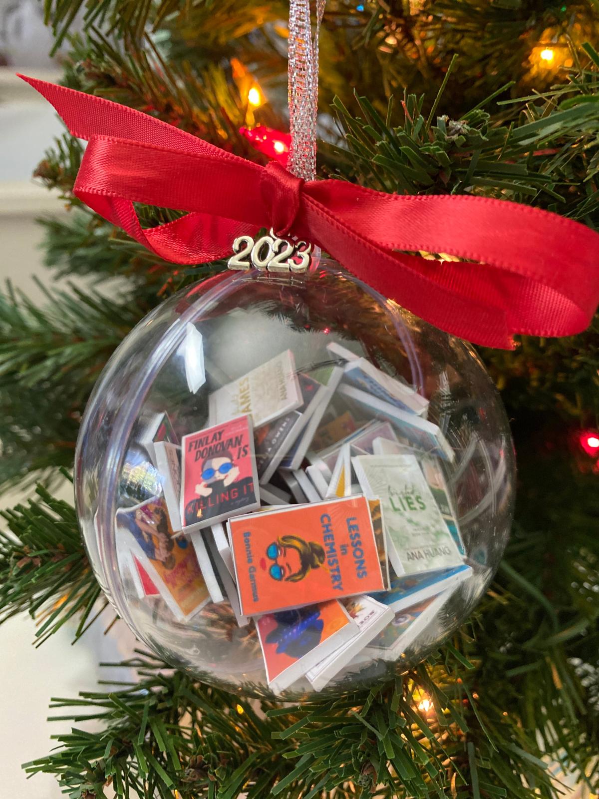 a clear ornament with tiny books inside hung on a Christmas tree