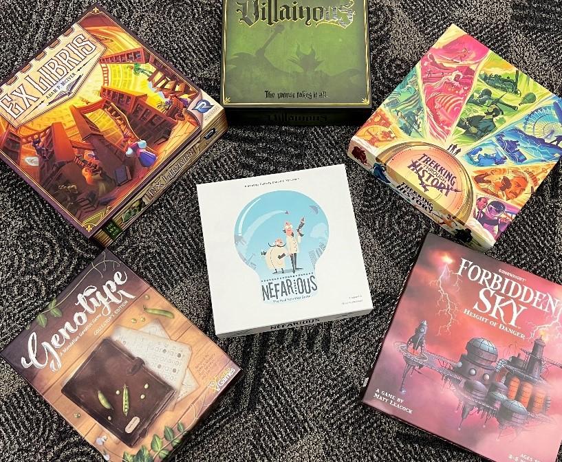 photo of five board game boxes encircling a sixth board game box on the floor