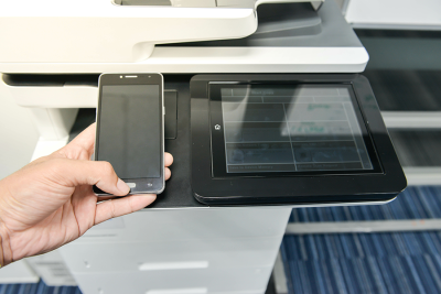 someone holding a smartphone next to a printer