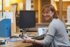Woman smiling while sitting at the circulation desk inside the library