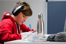 Tween boy with headphones on studying
