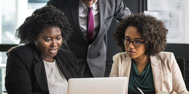 Two women and a man looking at a laptop screen