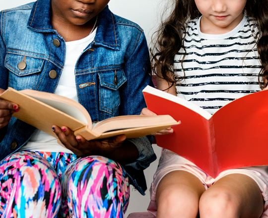 Boy and girl sitting side by side with open books