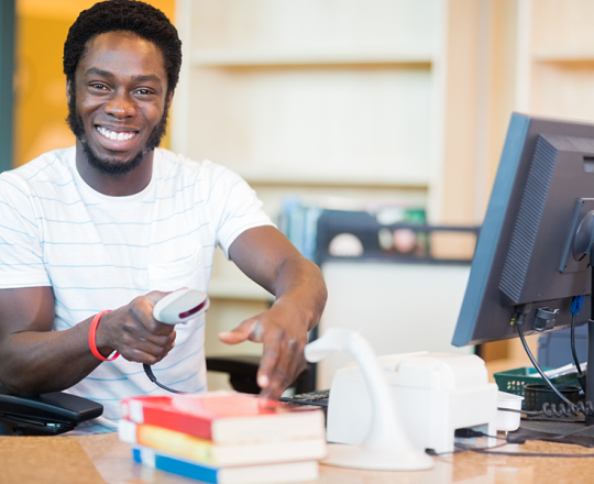 Man smiling as he scans books at the circulation desk