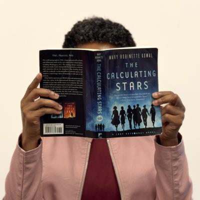 Monique Franklin holding up the book The Calculating Stars by Mary Robinette Kowal
