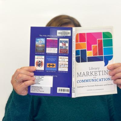 Sandy Johnson holding up a nonfiction book about marketing and communications